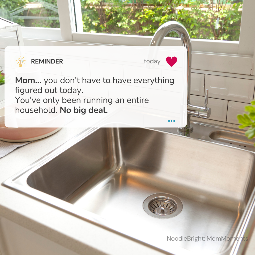 A stainless steel sink in a bright kitchen with a window, white subway tiles, and a chrome faucet. A white reminder card is overlaid on the upper left, reading a humorous message about not having everything figured out today.