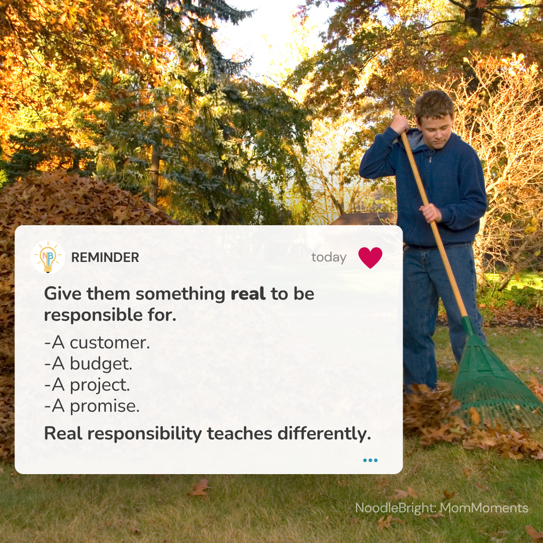 A boy in a blue sweatshirt and jeans uses a green rake in an autumn backyard, with a white reminder card overlay on the left containing text about assigning real responsibilities.